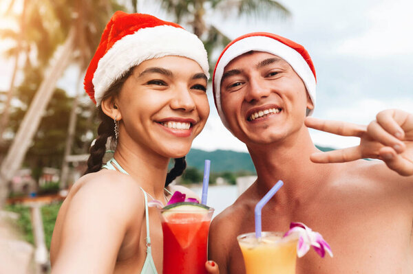 Happy smiling couple in christmas hats doing selfie