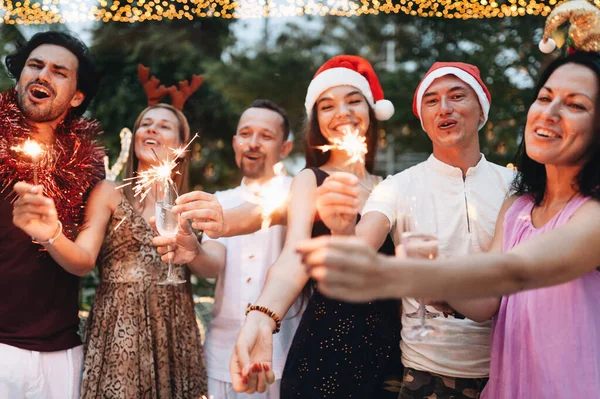 Grupo de amigos comemorando o Natal com brilhos e champanhe — Fotografia de Stock