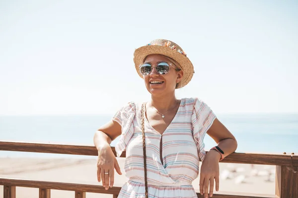 Woman in hat and sunglasses smiling enjoying summer day at viewpoint