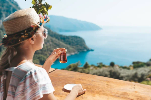Kobieta siedzi w kawiarni z pięknym widokiem i picia tradycyjnej tureckiej herbaty. — Zdjęcie stockowe