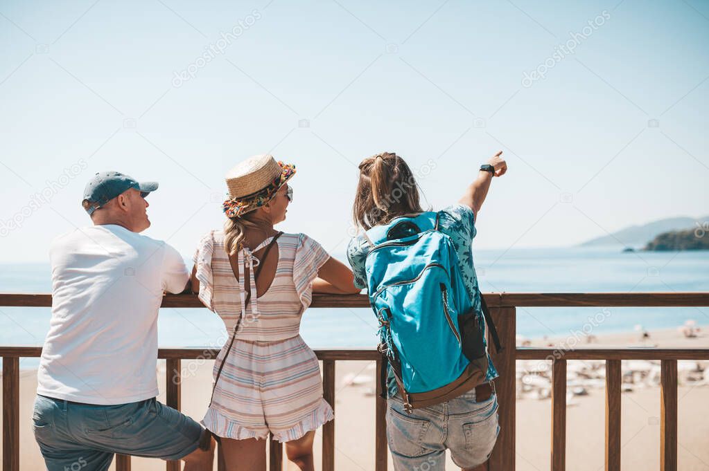 Three tourists standing at viewpoind and looking into the distance