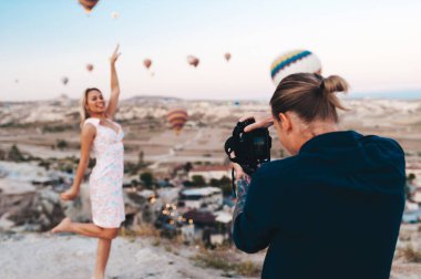 Photographer is taking shot of a woman at the background with Hot Air Balloons in Cappadocia clipart