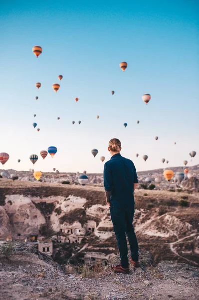 Türkiye 'de tatil yapan genç adam Kapadokya' da gündoğumu sırasında hava balonlarına bakıyor — Stok fotoğraf