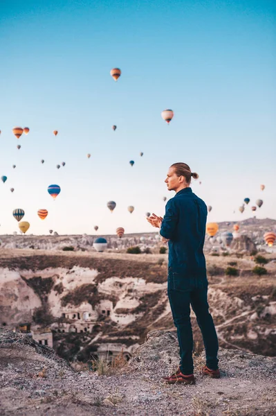Jovem em férias na Turquia Capadócia olhando para os balões de ar durante o nascer do sol em Kapadokya — Fotografia de Stock