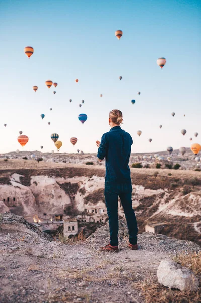 Türkiye 'de tatil yapan genç adam Kapadokya' da gündoğumu sırasında hava balonlarına bakıyor — Stok fotoğraf