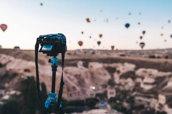 Balão de ar quente voando sobre a paisagem rochosa na Turquia. Foto câmera em um tripé em primeiro plano . — Fotografia de Stock