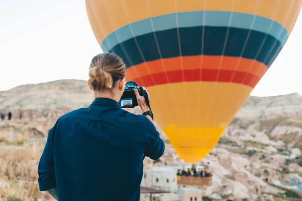 Ung man fotograf gör bilder av luftballonger vid soluppgången i Kappadokien — Stockfoto
