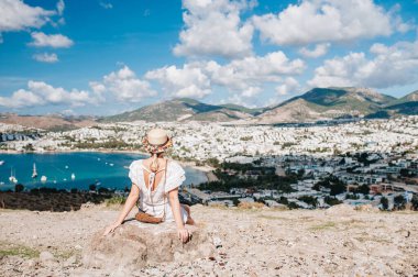 Bir kadın oturuyor ve yükseklerden Bodrum Körfezi 'nin muhteşem manzarasını izliyor..
