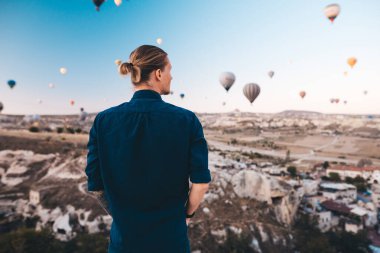 Türkiye 'de tatil yapan genç adam Kapadokya' da gündoğumu sırasında hava balonlarına bakıyor