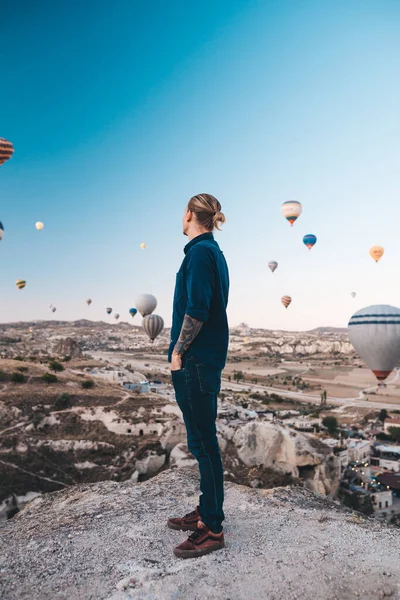 Młody mężczyzna na wakacjach w Turcji Kapadocja patrzy na balony podczas wschodu słońca w Kapadokya — Zdjęcie stockowe