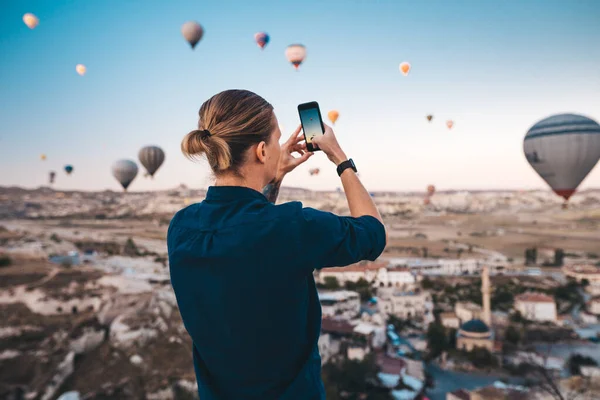 Mężczyzna robi zdjęcie pięknego krajobrazu i balonów w Kapadocji z aparatem mobilnym, czas wschodu słońca. — Zdjęcie stockowe