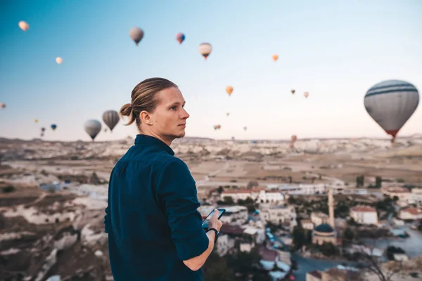 Młody mężczyzna na wakacjach w Turcji Kapadocja patrzy na balony podczas wschodu słońca w Kapadokya — Zdjęcie stockowe