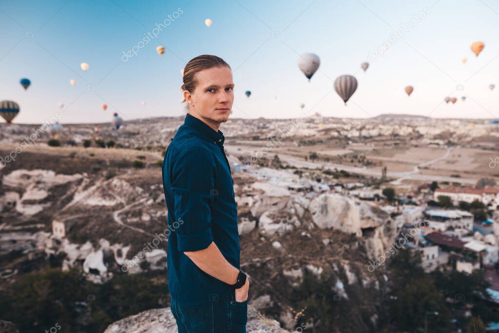 Young man on vacation in Turkey Cappadocia looking at the air balloons during Sunrise at Kapadokya