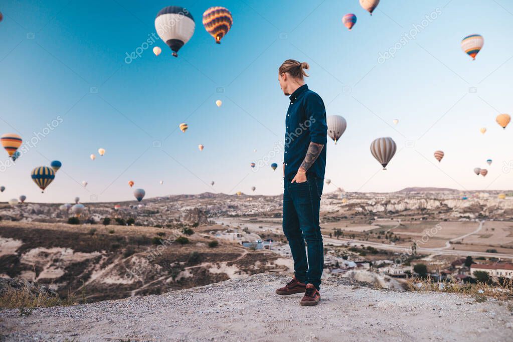 Young man on vacation in Turkey Cappadocia looking at the air balloons during Sunrise at Kapadokya