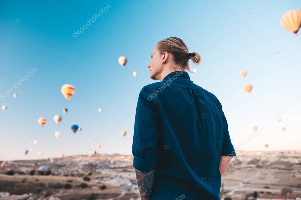 Young man on vacation in Turkey Cappadocia looking at the air balloons during Sunrise at Kapadokya