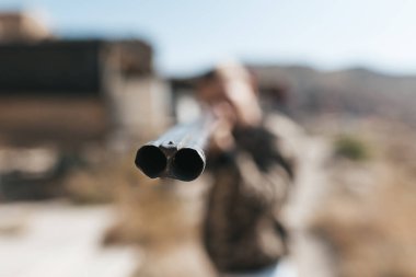 Kamuflaj elbiseli erkek avcı av tüfeğiyle avlanmaya hazır.