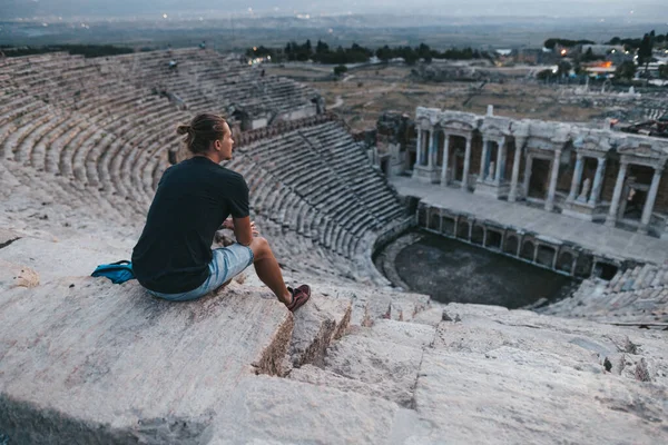 Az ember ül a lépcsőn az ősi amfiteátrum az ókori város Hierapolis, Törökország — Stock Fotó