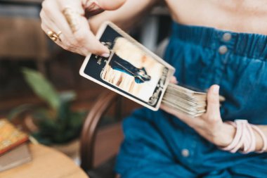 Kadın kafede masada Tarot kartları okuyor.