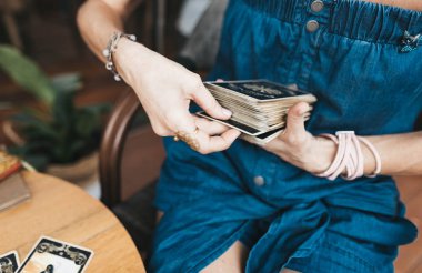 Kadın kafede masada Tarot kartları okuyor.