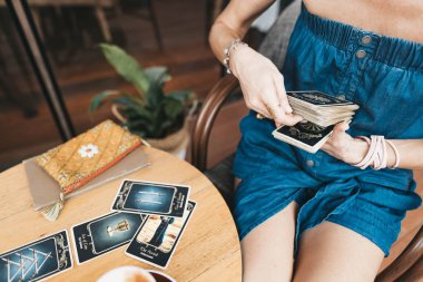 Kadın kafede masada Tarot kartları okuyor.