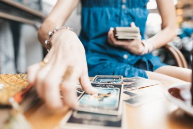Kadın kafede masada Tarot kartları okuyor.