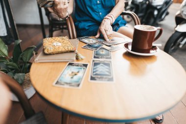 Kadın kafede masada Tarot kartları okuyor.
