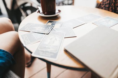 Kadın kafede masada Tarot kartları okuyor.