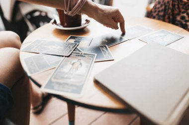 Kadın kafede masada Tarot kartları okuyor.