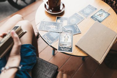 Kadın kafede masada Tarot kartları okuyor.