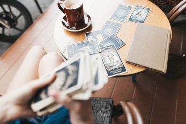 Kadın kafede masada Tarot kartları okuyor.