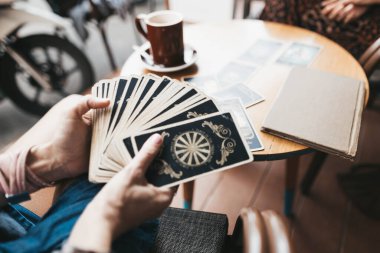 Kadın kafede masada Tarot kartları okuyor.