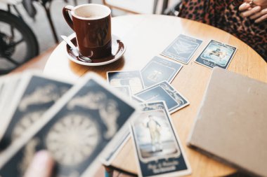 Kadın kafede masada Tarot kartları okuyor.