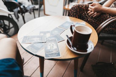 Kadın kafede masada Tarot kartları okuyor.