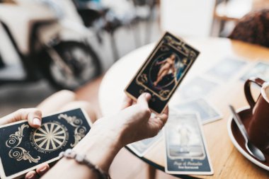 Kadın kafede masada Tarot kartları okuyor.