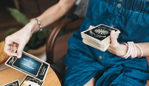 Kadın kafede masada Tarot kartları okuyor.