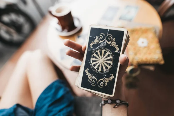 Kadın kafede masada Tarot kartları okuyor.