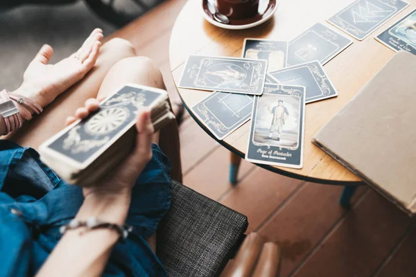 Μια γυναίκα διαβάζει κάρτες Ταρώ στο τραπέζι στο καφέ. — Φωτογραφία Αρχείου