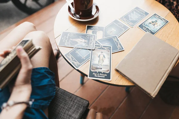 Kadın kafede masada Tarot kartları okuyor.