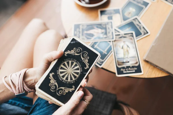 Kadın kafede masada Tarot kartları okuyor.