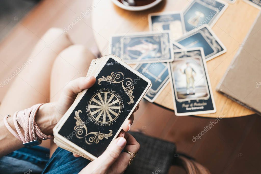 Woman is reading Tarot cards on the table in cafe
