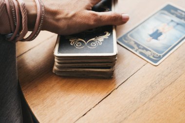 Kadın kafede masada Tarot kartları okuyor.