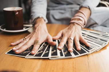 Kadın kafede masada Tarot kartları okuyor.