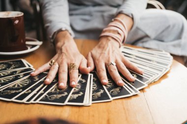 Kadın kafede masada Tarot kartları okuyor.