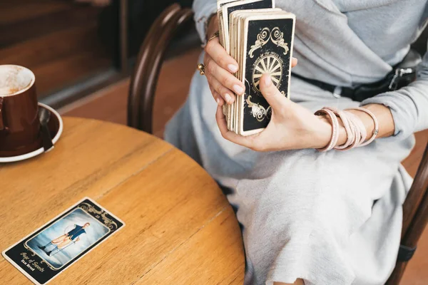Μια γυναίκα διαβάζει κάρτες Ταρώ στο τραπέζι στο καφέ. — Φωτογραφία Αρχείου