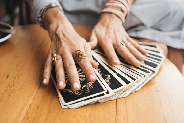 Kadın kafede masada Tarot kartları okuyor.
