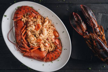 Siyah ahşap zemin üzerinde ıstakoz eti olan makarna.