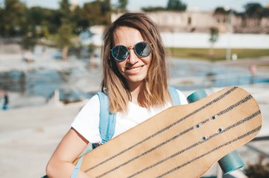 Güneş gözlüklü çekici bir kadının portresi. Elinde uzun panoyla gülümsüyor.