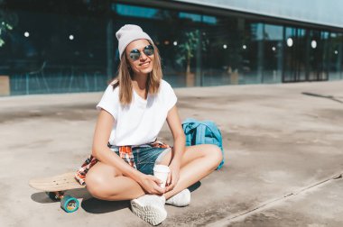 Güneş gözlüklü çekici bir kadın. Uzun tahta üzerinde oturup rahatlıyor.