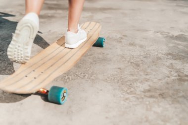 Dışarıdaki bir sörf tahtasının üzerinde spor ayakkabılı kadın bacaklarının yakın çekimi.