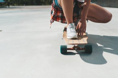 Dışarıdaki bir sörf tahtasının üzerinde spor ayakkabılı kadın bacaklarının yakın çekimi.